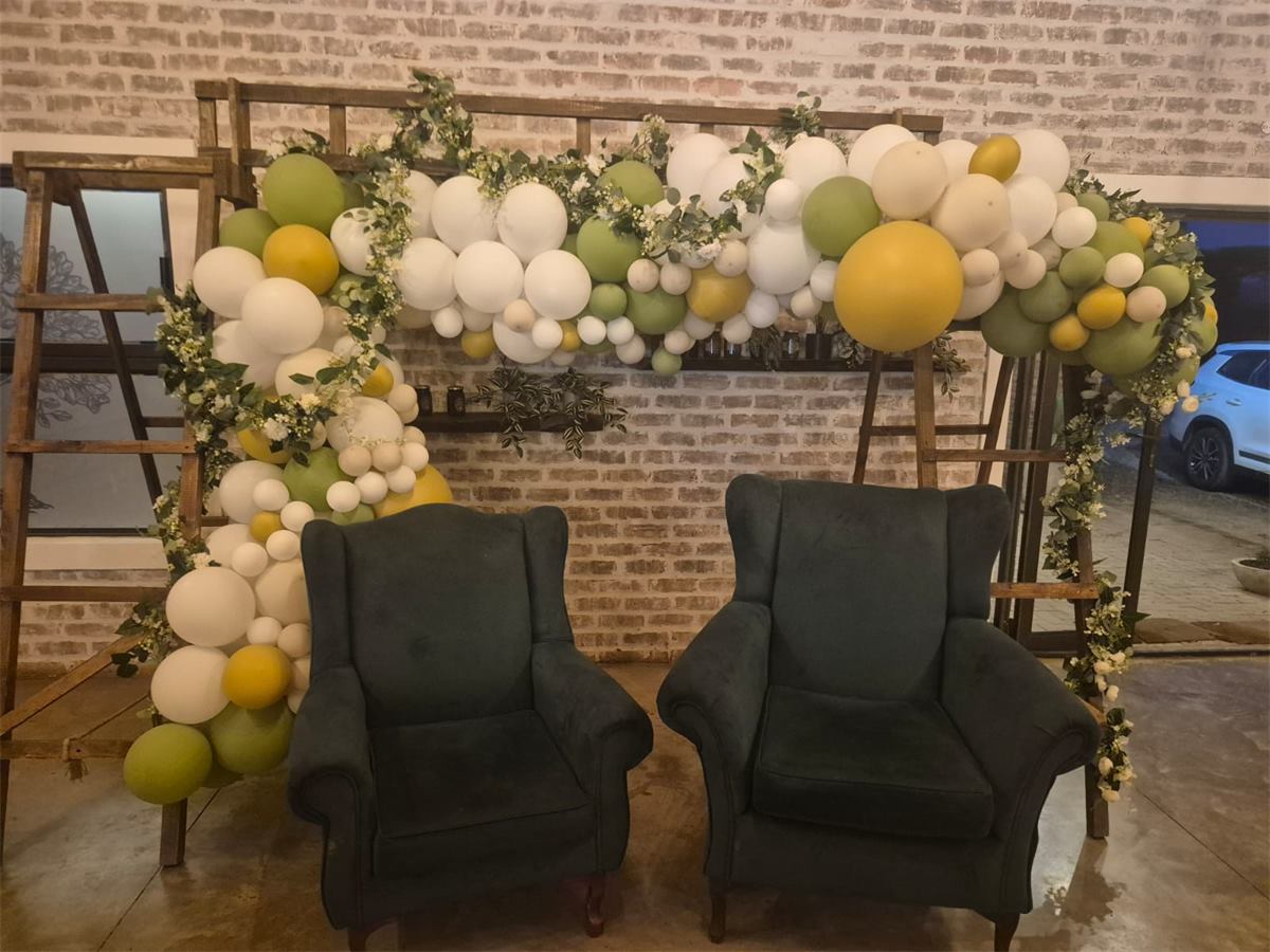 Green and white balloon arch with two velvet armchairs for a birthday party