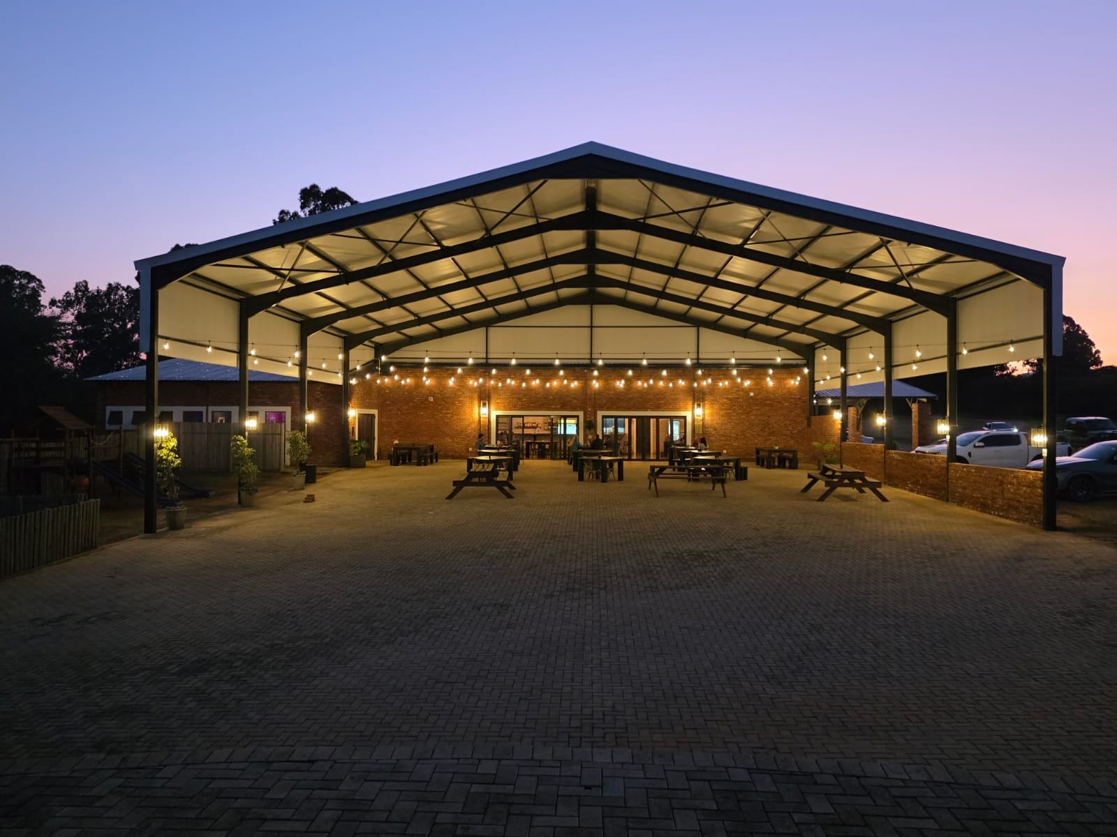 The covered pavilion at dusk with the lights on