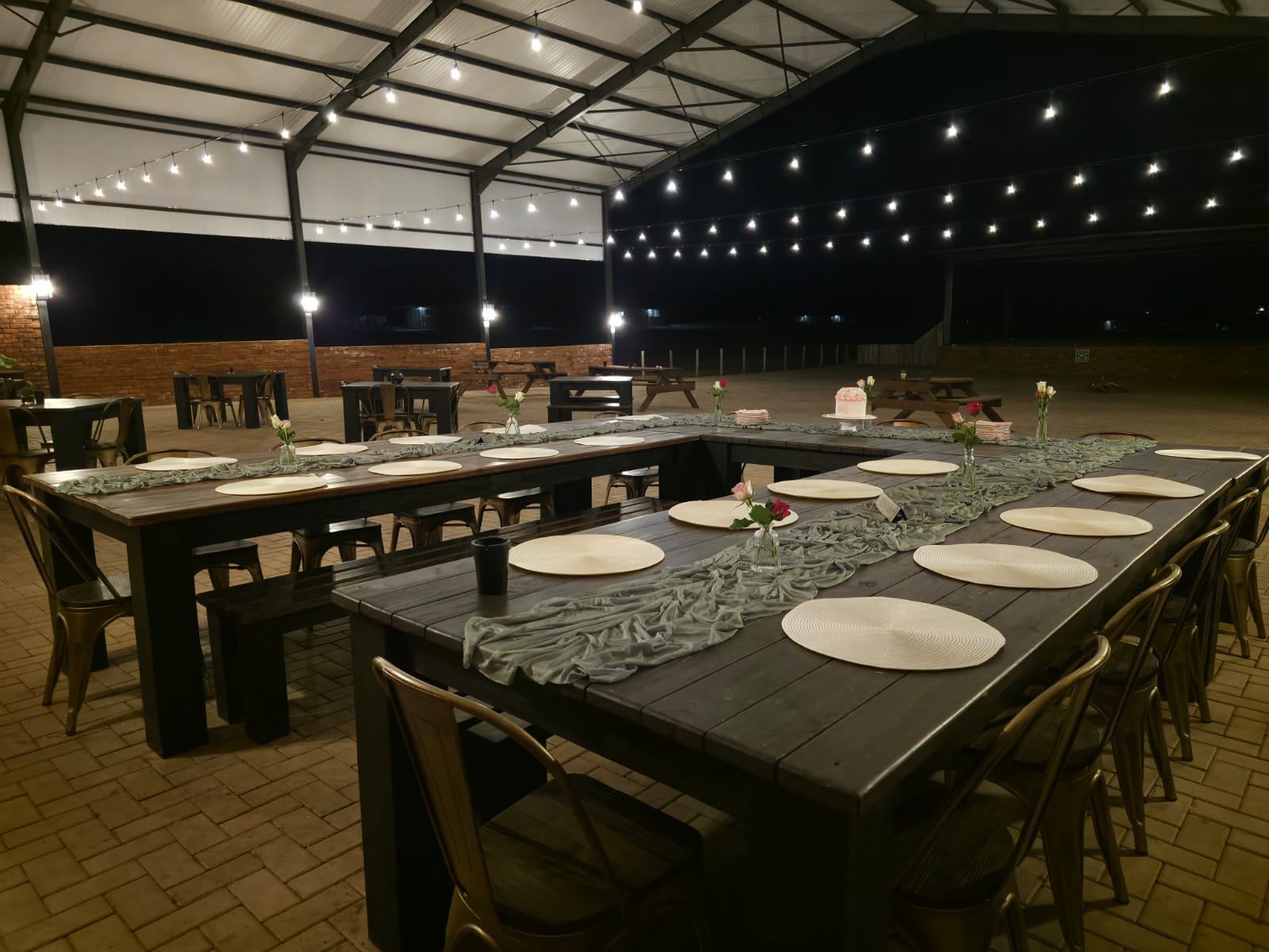 The covered pavilion at night with long tables under string lights